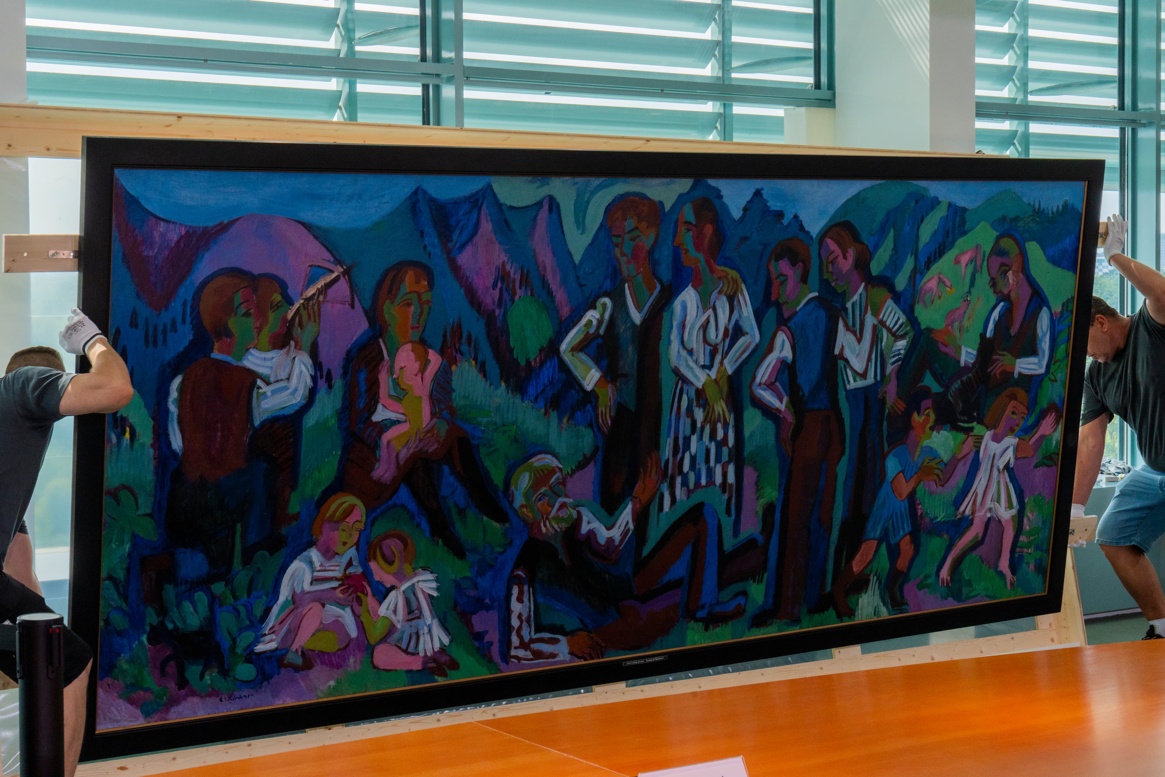 Das Gemälde Sonntag der Bergbauern von Ernst Ludwig Kirchner wird im Kabinettssaal im Berliner Bundeskanzleramt in seinen Transportrahmen befestigt.
